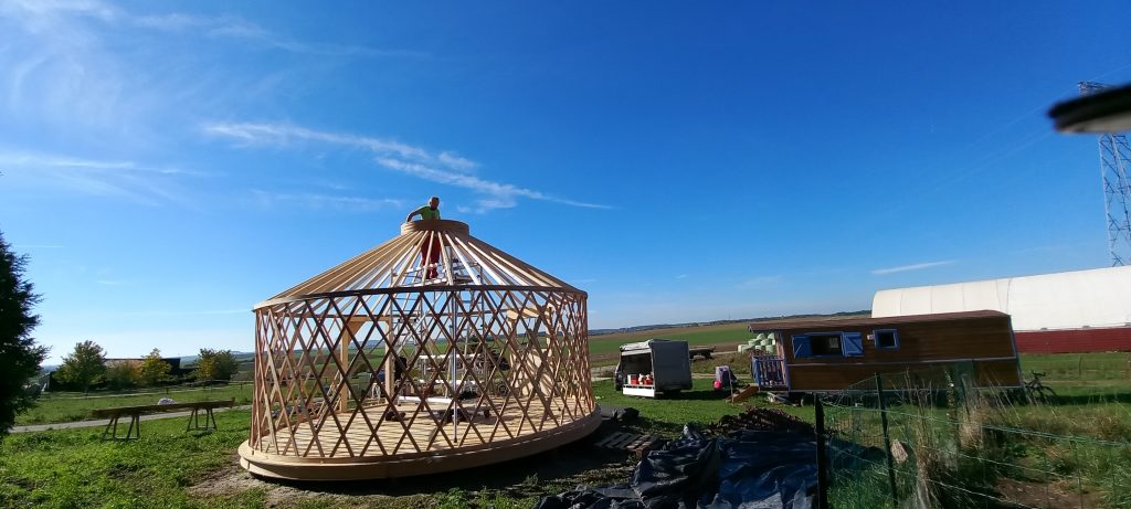 ciel bleu et ossature en bois d'une yourte contemporaine pendant chantier de montage