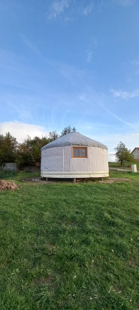 vue de l'extérieur d'une jolie yourte avec fenêtre et toile grise dans contexte agricole
