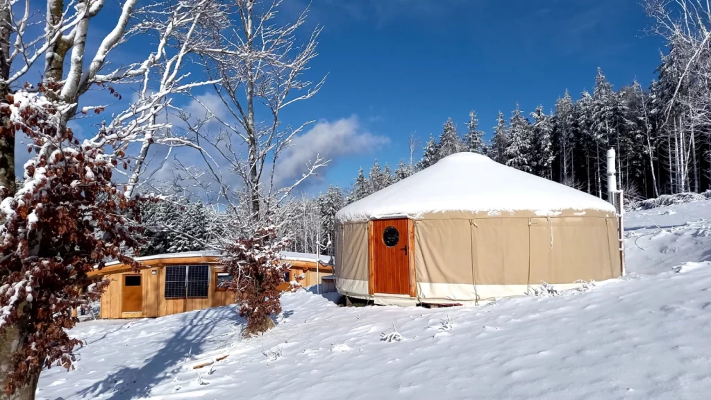 Yourte contemporaine installée en montagne sous la neige, réalisation écoresponsable