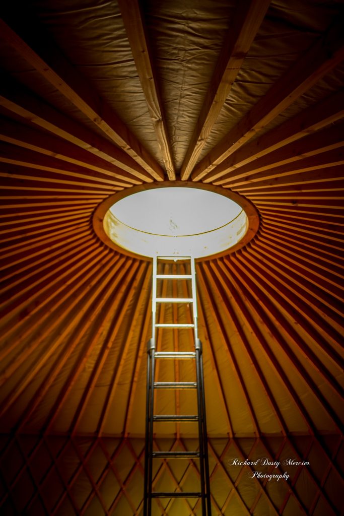 le puits de lumière ou toono d'une yourte contemporaine avec une échelle lors du montage