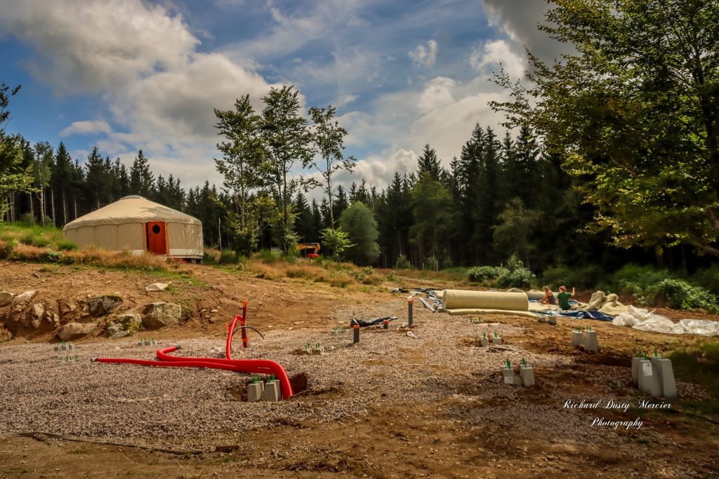raccordements en eau et fondations d'un chalet avec une yourte en arrière plan