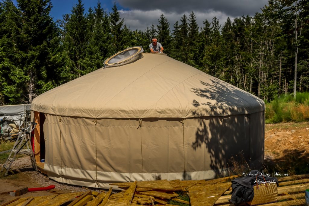 artisan en train de poser un skydôme coupole sur le puits de lumière d'une yourte