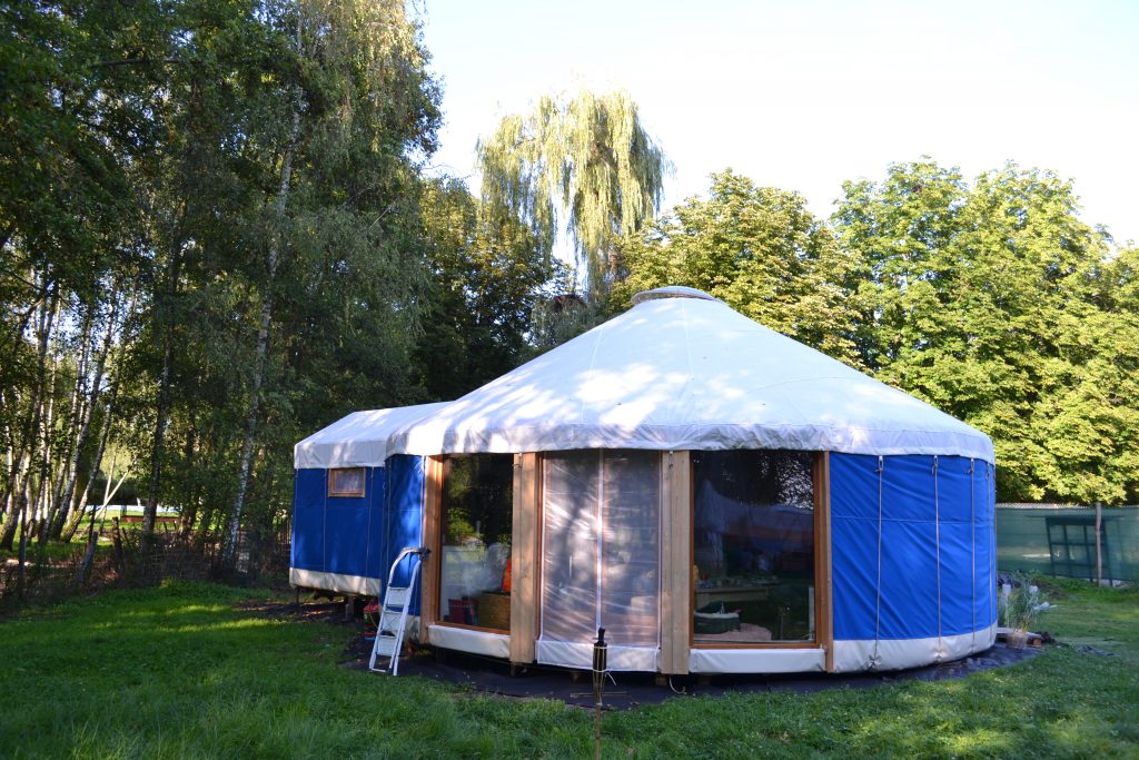 yourte contemporaine d'habitation bleue avec grande baie vitrée et cabanon sanitaire accollé
