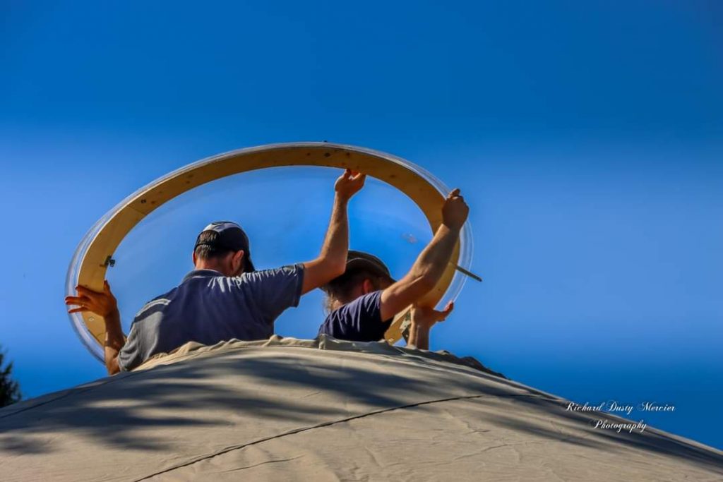 deux personnes sont en train de poser un skydôme sur le puits de lumière d'une yourte contemporaine des ateliers turmgaessel