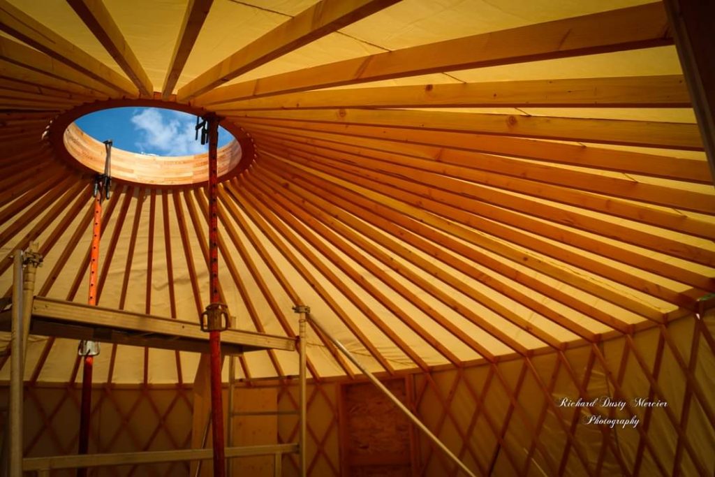 ossature en bois d'une yourte contemporaine avec toile intérieure posée et lumière à travers le tissu